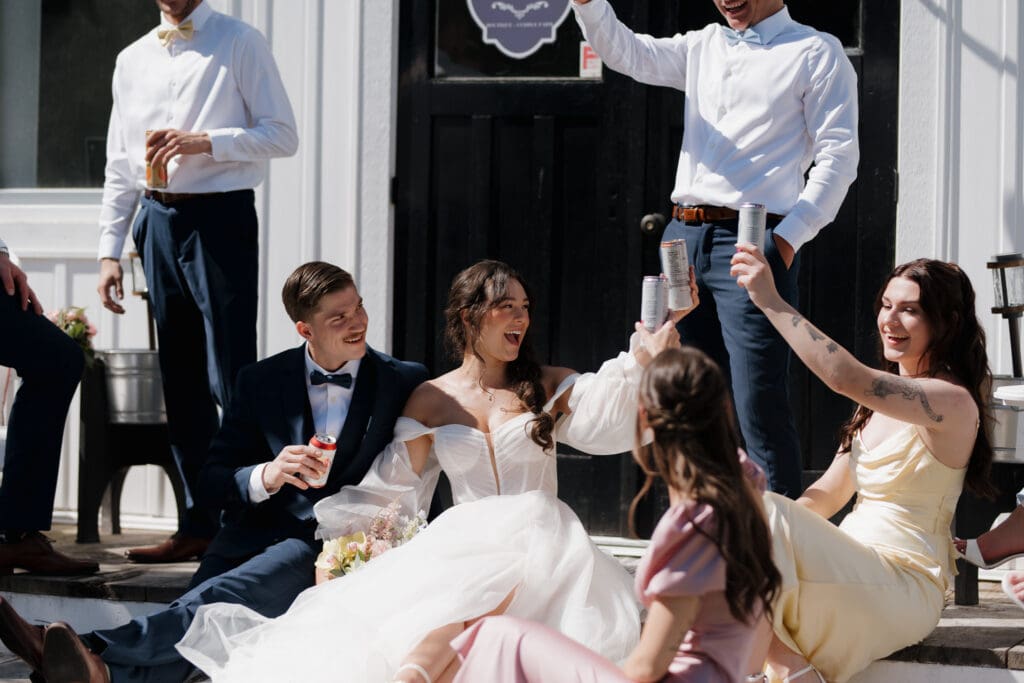 Hayley Zumkeller photography and videography team from Victoria BC capture a wedding party celebration following their Nanaimo outdoor wedding ceremony. The bridesmaid's gowns are in a variety of pastel colours while the groomsman are coatless. The lush surroundings of Puska Properties show in the background.