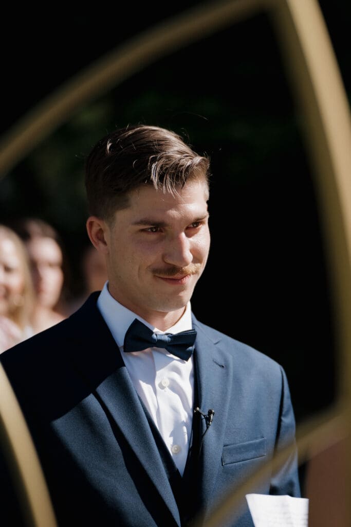 Hayley Zumkeller photography and videography team from Victoria BC capture a groom looking down the aisle at his soon to be wife lovingly, with tears in his eyes, at the start of their Nanaimo outdoor wedding ceremony.