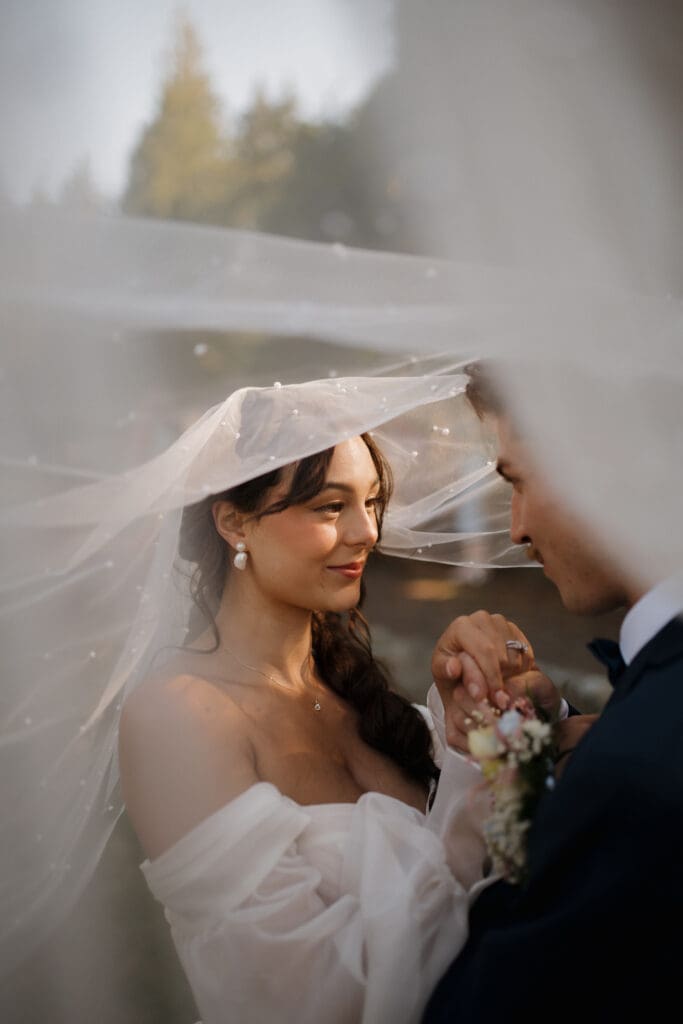 Hayley Zumkeller photography and videography team from Victoria BC capture a bride and groom sharing an intimate moment under the bride's veil following their Nanaimo outdoor wedding at Puska Properties.