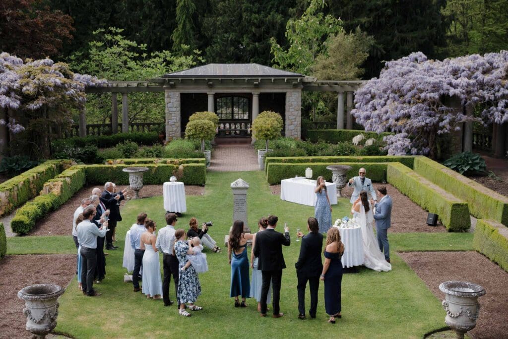 Hatley Castle Wedding in Victoria BC captured by local Wedding Photographer Hayley Zumkeller - Wedding Cocktail Hour and Reception taking place in the Italian Gardens where the couple is doing a champagne toast