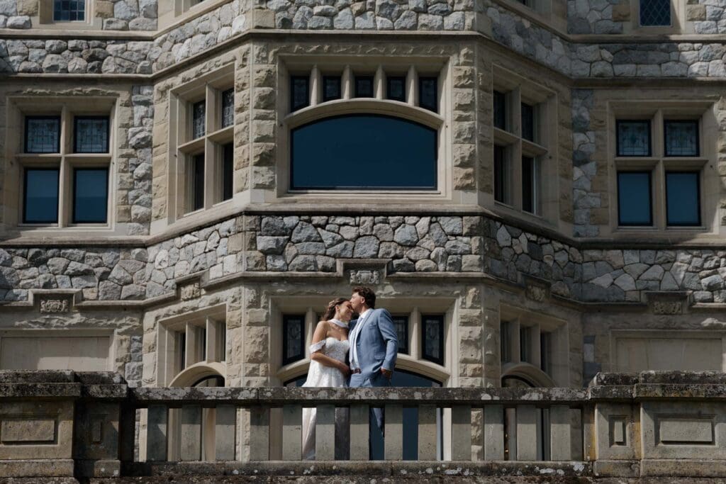 Luxury Vancouver Island wedding held at Hatley Castle in Victoria BC. This image captured by Hayley Zumkeller photography and videography team shows the bride and groom kissing on the balcony showing off the historical features of Hatley Castle.  