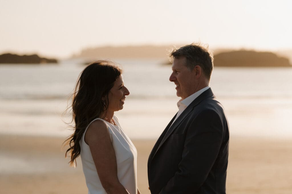 Hayley Zumkeller photography and videography team capture a newly married couple gazing lovingly into each other's eyes with the beautiful golden hour glow surrounding them. In the background you can see Chesterman Beach.