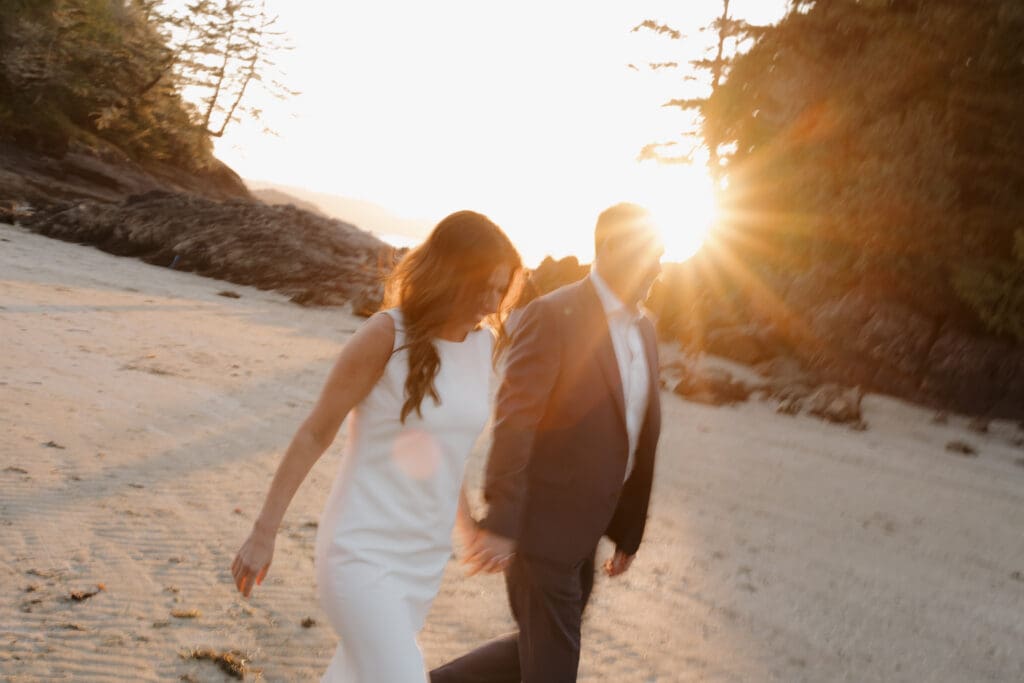 Hayley Zumkeller photography and videography team capture a newly married couple walking hand in hand with the beautiful golden hour glow surrounding them. In the background you can see Chesterman Beach.