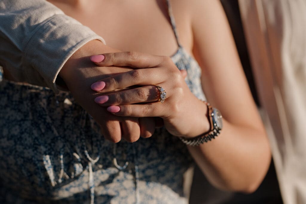 Victoria BC photography and videography team from Victoria BC capture the clasped hands of a newly engaged couple at Ogden Point Breakwater on Vancouver Island