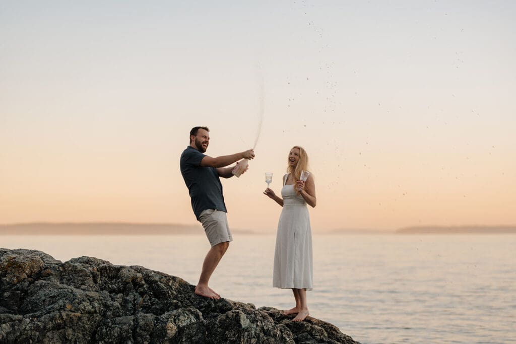 Hayley Zumkeller Victoria BC Proposal Photographer captures a couple celebrating their private proposal beach side with champagne