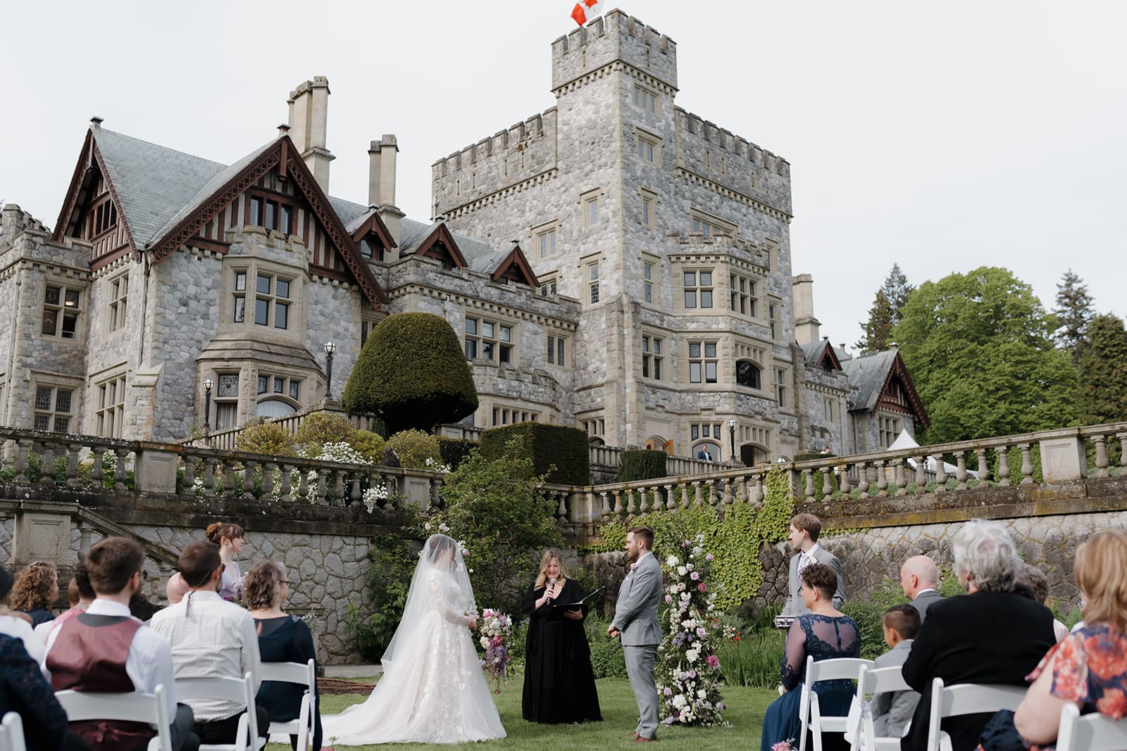 Hatley Castle wedding photography in Victoria BC shot by Hayley Zumkeller, Wedding Photography and Videography Team. The couple is at the altar, surrounded by their guests, on the majestic Hatley Castle lawns.