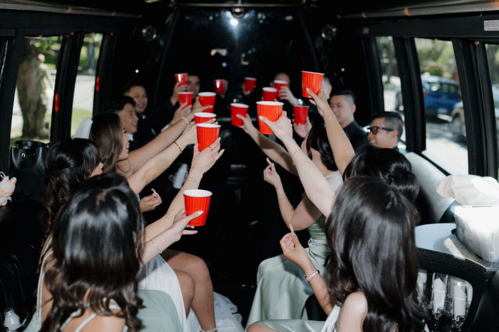 Hayley Zumkeller, Victoria BC Wedding Videographer and Photographer captures a wedding party as they make a toast in the limo through downtown Victoria BC on their way to Parliament to capture wedding party photos.