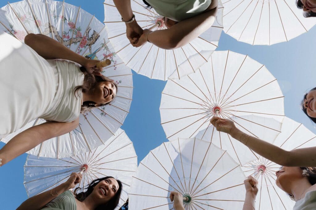 Hayley Zumkeller, Victoria BC Wedding Videographer and Photographer and team capture a shot underneath the parasols during wedding party photos on the Parliament grounds on Vancouver Island.