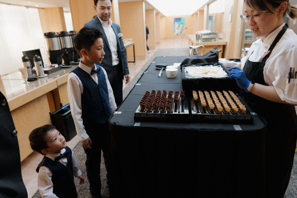 Hayley Zumkeller, Victoria BC Wedding Videographer and Photographer and team capture the mini ice cream bar with some of the young children checking it out during the reception at a mini-destination wedding at Laurel Point Inn on Vancouver Island.
