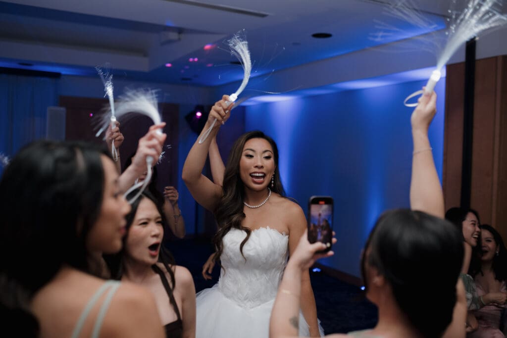 Hayley Zumkeller, Victoria BC Wedding Videographer and Photographer captures the high energy dance party at a wedding reception at Laurel Point Inn in Victoria BC. The bride is surrounded by friends with sparklers, laughing and having a great time.