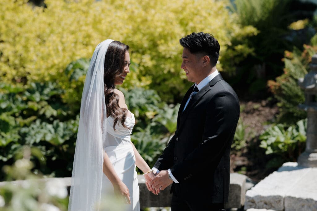 Hayley Zumkeller, Victoria BC Wedding Videographer and Photographer captures a private moment following the first look between a bride and groom at the waterfall feature at Laurel Point Inn on Vancouver Island during their mini-destination wedding.