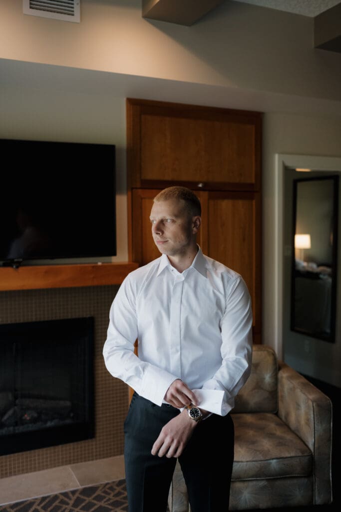 Hayley Zumkeller photography and videography team from Victoria BC capture getting ready photos for a wedding day at Olympic View Golf Course. In this image the groom is finishing his cufflinks in anticipation of the upcoming ceremony.