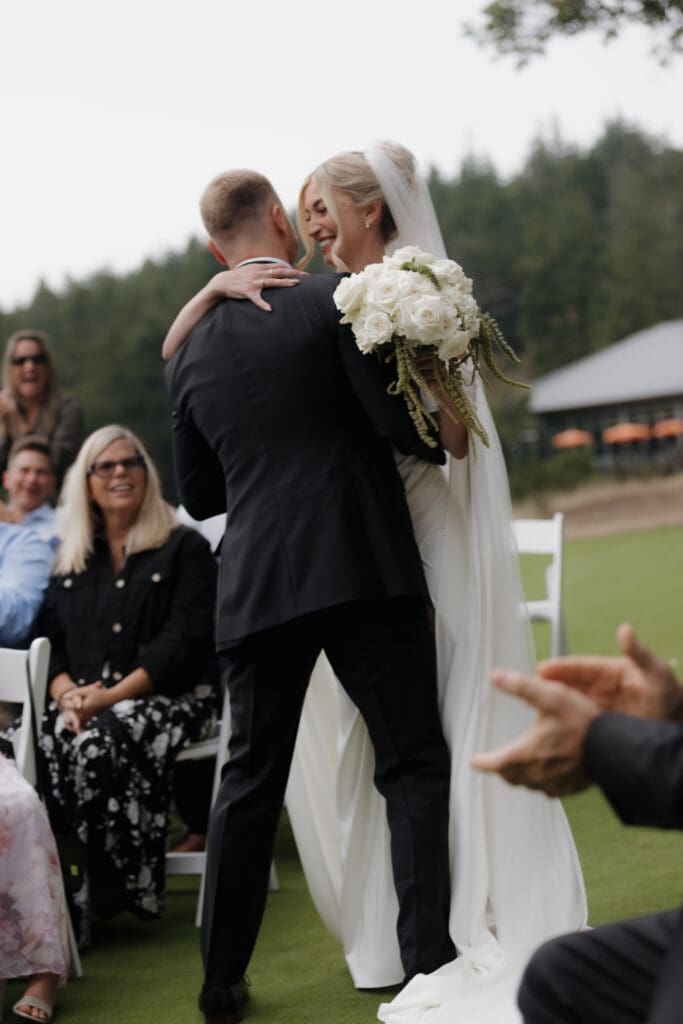 Hayley Zumkeller photography and videography team capture a sweet, romantic moment between the bride and groom just following the ceremony when he lifts her into the air for an embrace.