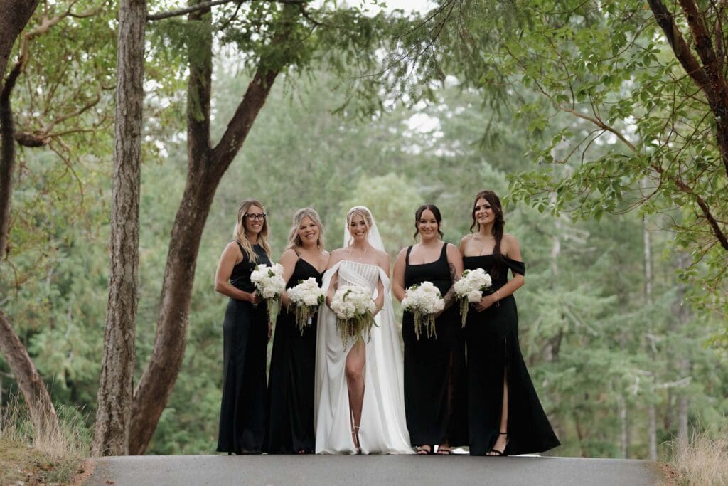 Hayley Zumkeller photography and videography team from Victoria BC capture an elegant image of a bride with her bridesmaids among the tree at Olympic View Golf Course.