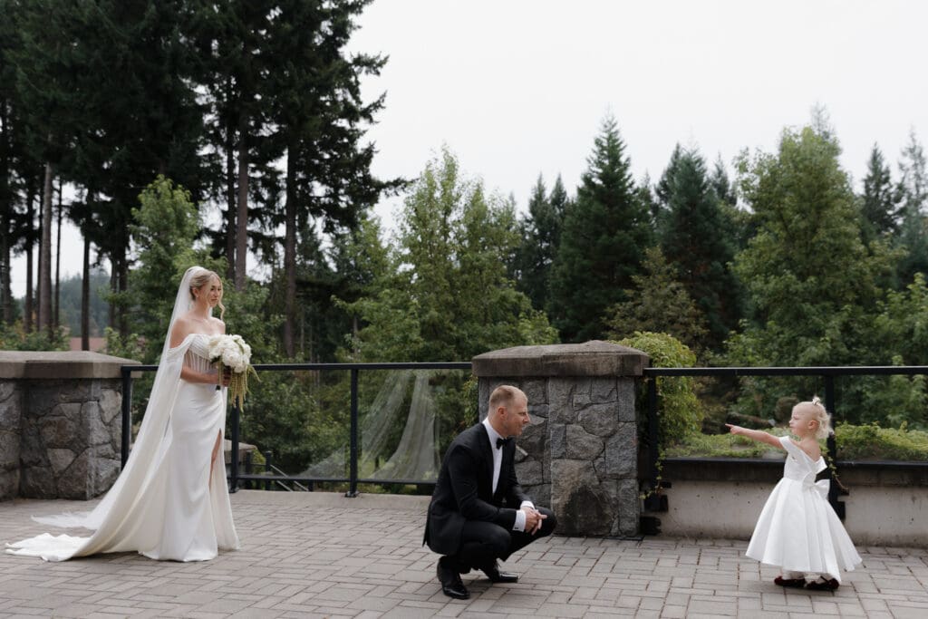 Hayley Zumkeller photography and videography team from Victoria BC capture the first look moment between a bride and groom, joined by their daughter as the daughter points out her mom standing behind her dad in this heartwarming image of a family joining together.