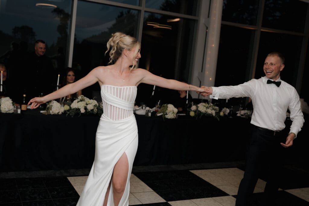 Hayley Zumkeller photography and videography team capture the first dance between a bride and groom at their reception at Olympic View Golf Course on Vancouver Island among white sheer drapery from the ceiling with twinkly lights shining through.
