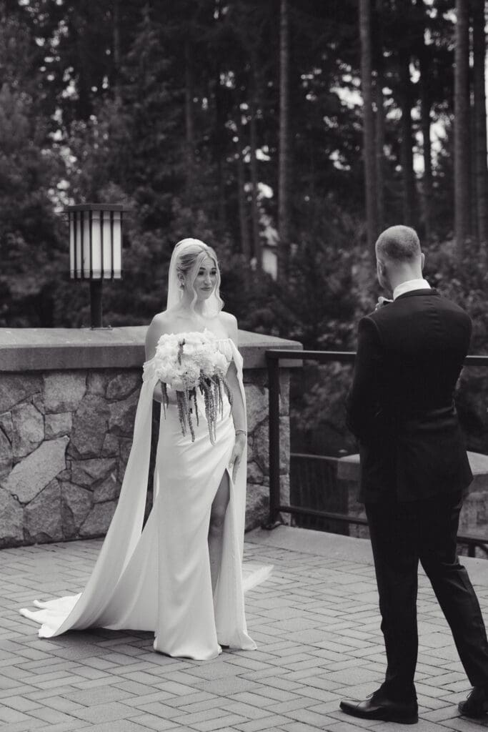 Hayley Zumkeller Photography & Videography team capture an elegant wedding on Vancouver Island. In this black and white image the groom turns for the first look of his bride and is overcome with emotion as he sees her in her stunning dress.