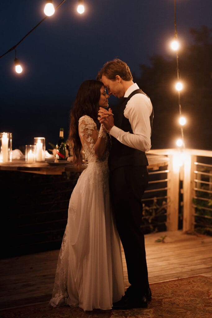 The first dance of a bride and groom during their intimate elopement ceremony on Vancouver Island, captured by Hayley Zumkeller photography and videography team. They are dancing closely among twinkling lights and candles.