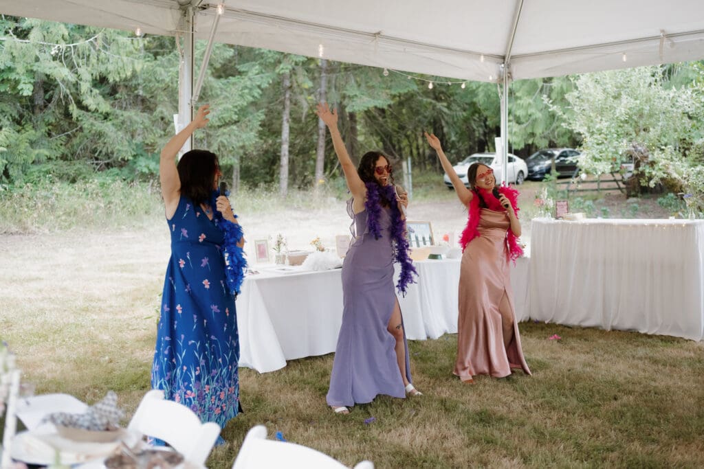 A theatrical speech and dance performance during a couple's reception on Vancouver Island is captured by Hayley Zumkeller photography and videography team from Victoria BC. The women, dressed in colourful gowns of blue, purple and red are having a fun time dancing and singing to the couple on a private property in Nanaimo BC.