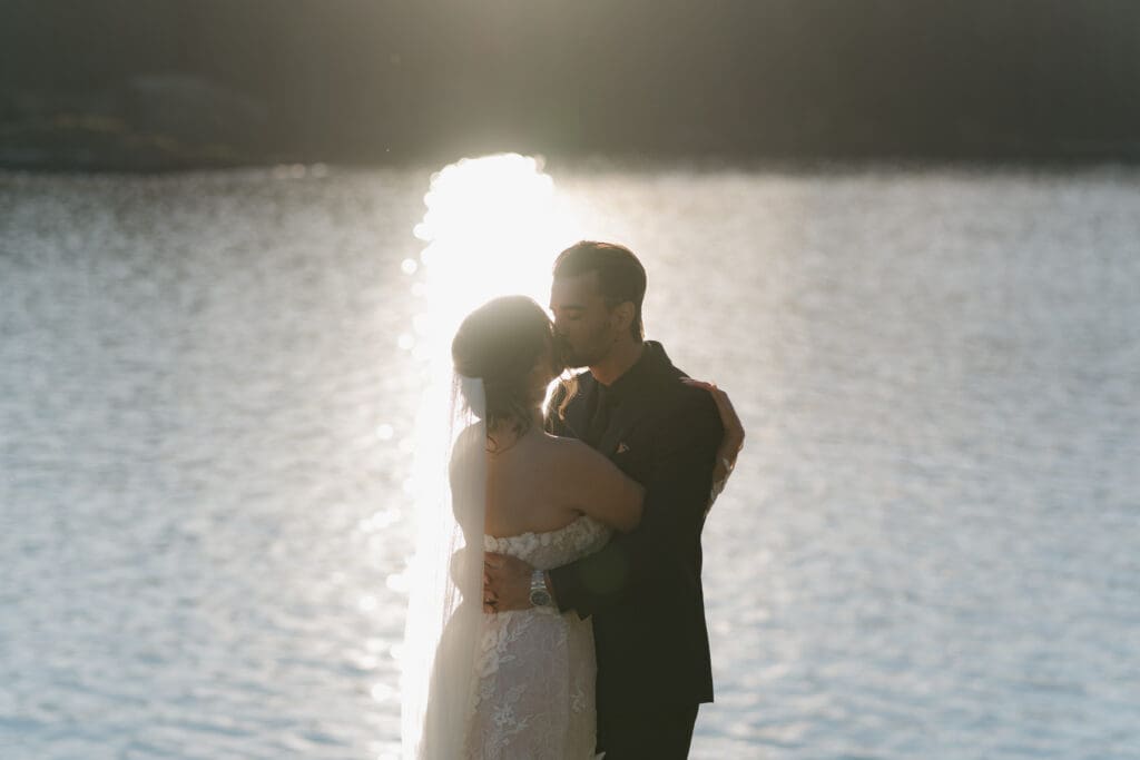 Hayley Zumkeller photography and videography team from Victoria BC capture a couple kissing as the sun set over the water behind them. This image was taken as part of the "life happens" guarantee because it was raining on their wedding day. Just one of the many perks of hiring a professional photography and videography team on Vancouver Island.