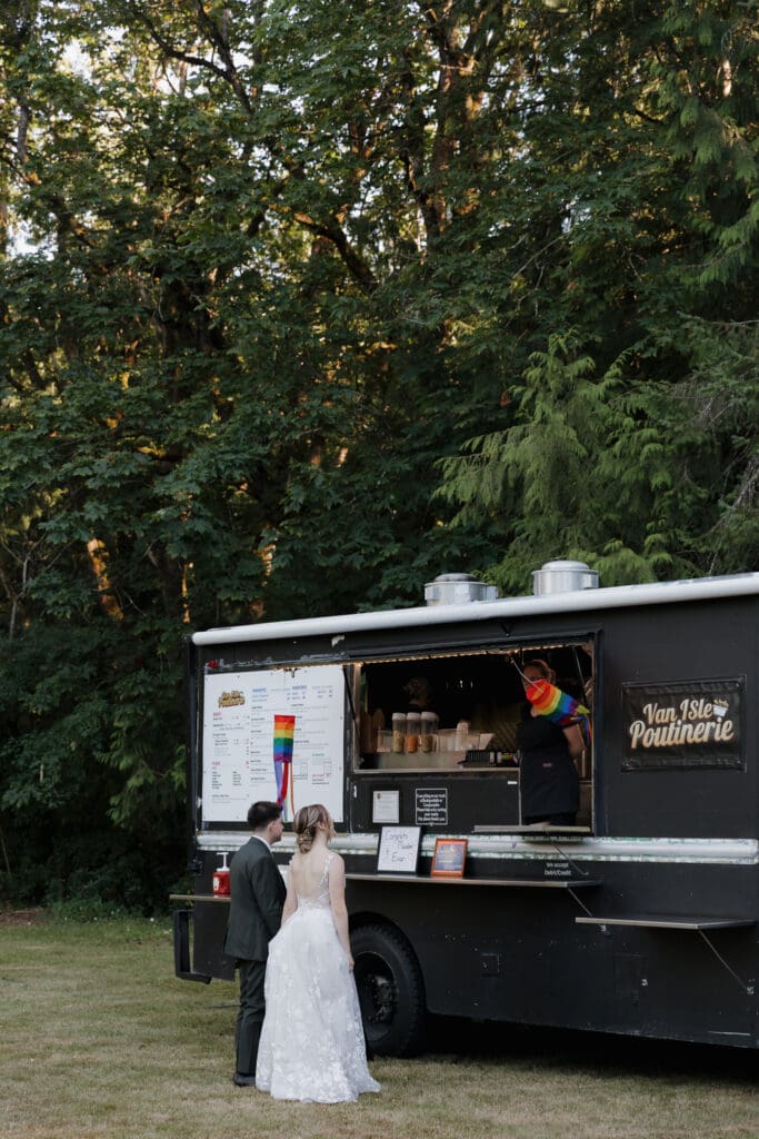 Hayley Zumkeller photography and videography team from Victoria BC capture this image of the bride and groom getting poutine (a classic Canadian treat) at the food truck for their wedding reception on Vancouver Island.