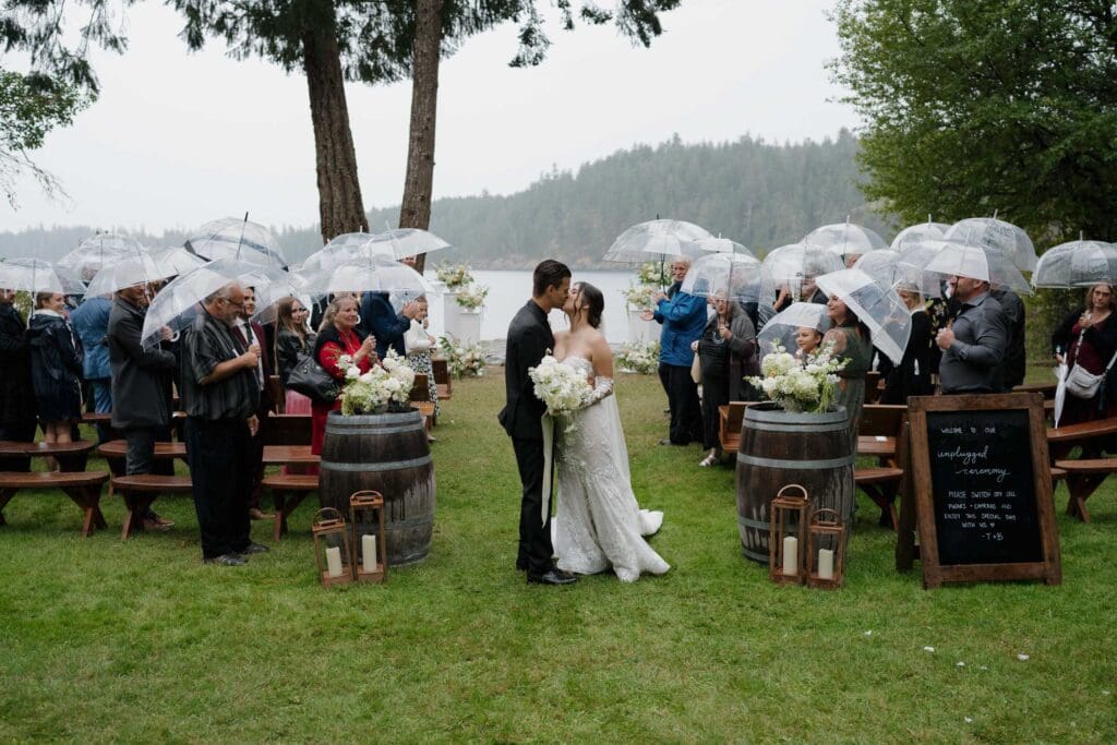 Hayley Zumkeller photography and videography team from Victoria BC capture a bride and groom kissing as they leave the ceremony with the ocean backdrop at Gowlland Harbour Resort on Vancouver Island.