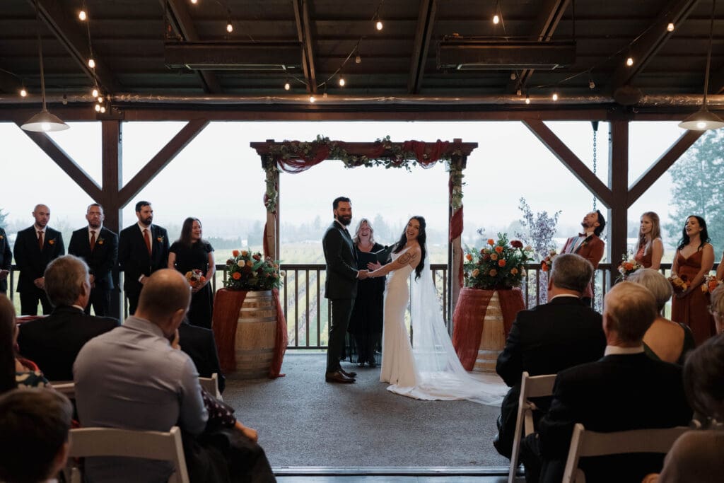 Wedding ceremony at Church and State Winery Victoria BC with vineyard rows in the background