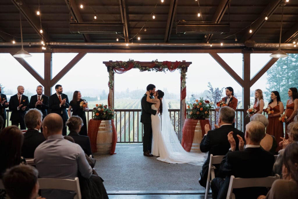 Hayley Zumkeller photography and videography team from Victoria BC captures a first kiss by a bride and groom during this misty fall wedding at Church and State Winery on Vancouver Island.