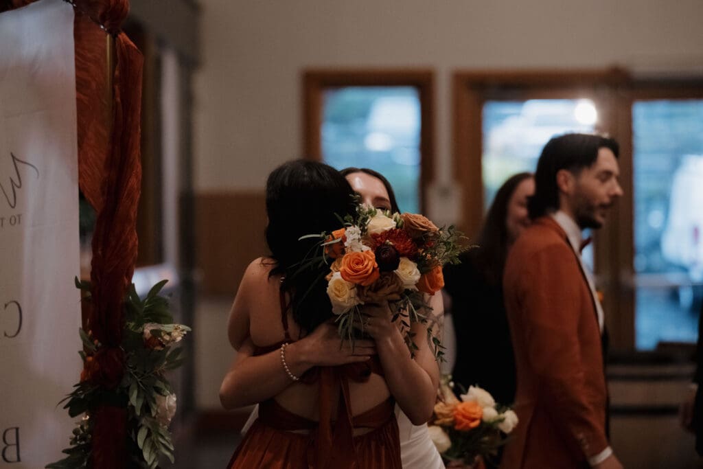 Hayley Zumkeller photography and videography team from Victoria BC captures a bride embracing her bridesmaid following the Church and State winery wedding ceremony on Vancouver Island.