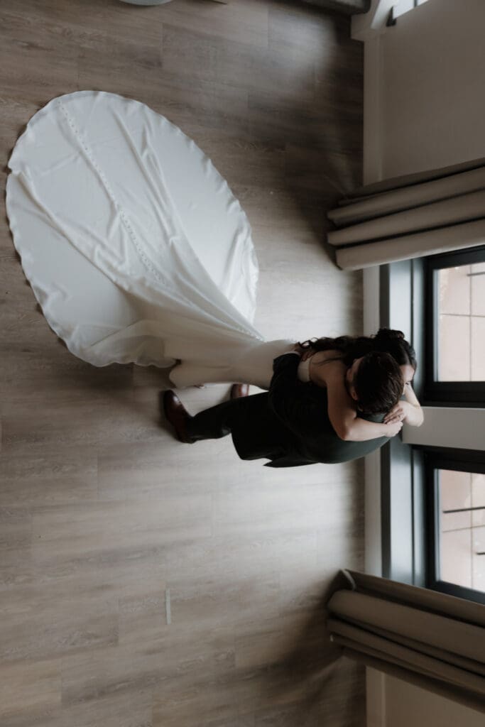 Hayley Zumkeller photography and videography team from Victoria BC capture the emotional embrace between a bride and groom during their first look. The image is artistically captured from above, with the bride's train on full display, at Delta Ocean Pointe on Vancouver Island.