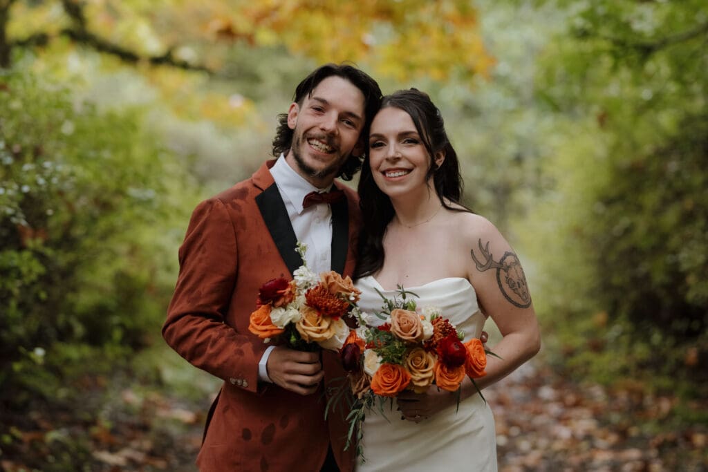 Hayley Zumkeller photography and videography team from Victoria BC captures a bride with her brother (dressed in a deep orange tuxedo in keeping with the Fall vibes of this October Wedding) in the forest at Church and State Winery on Vancouver Island.