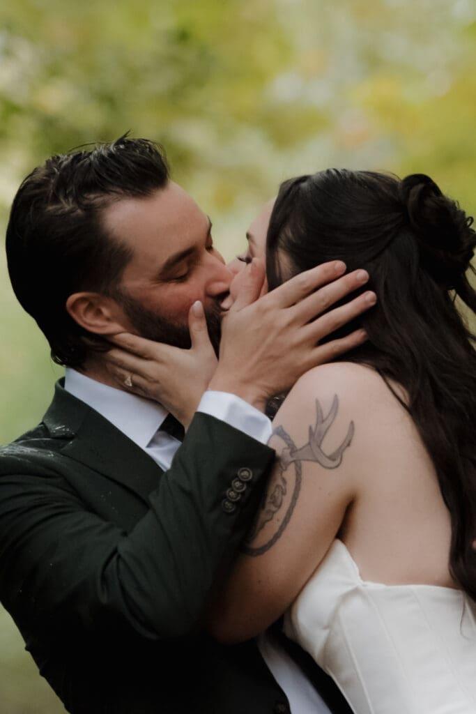 Hayley Zumkeller photography and videography team from Victoria BC captures a bride and groom sharing an emotional kiss during their private vows in the forest at Church and State Winery in the rain.
