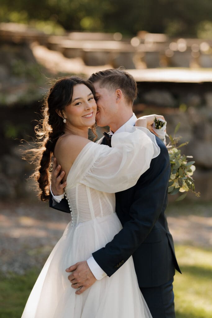 Hayley Zumkeller photography and videography team capture a husband and wife following their wedding, with the golden hour rays filtering through the trees in the background.