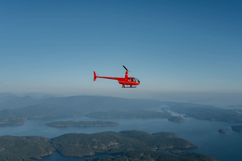 Helicopter flying over mountains during Vancouver Island helicopter elopement in British Columbia.