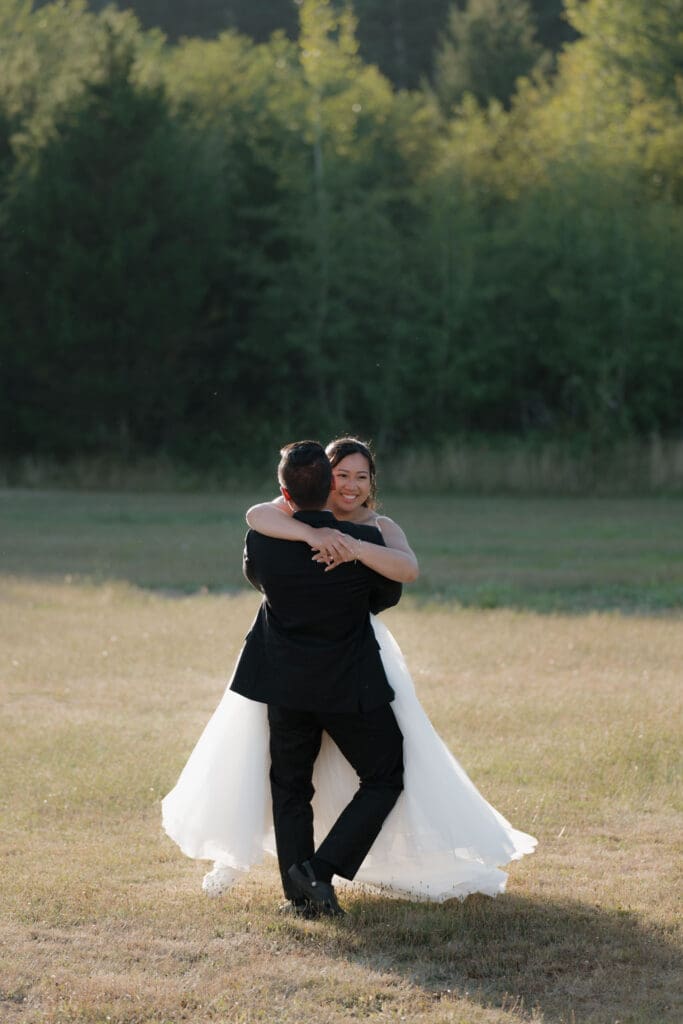 Hayley Zumkeller photography and videography team from Victoria BC capture the emotional connection of a couple during their engagement photography session + helicopter elopement on Vancouver Island. This natural and candid moment of the bride running into her groom's arms with the golden sun in the backdrop is breathtaking.