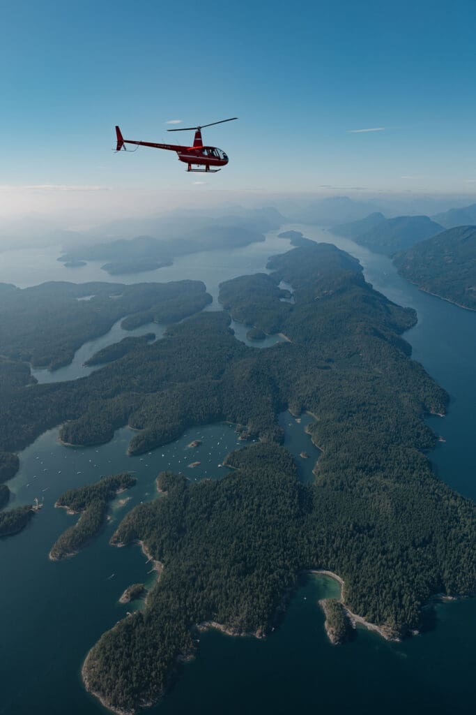 Helicopter flying over mountains during Vancouver Island helicopter elopement in British Columbia