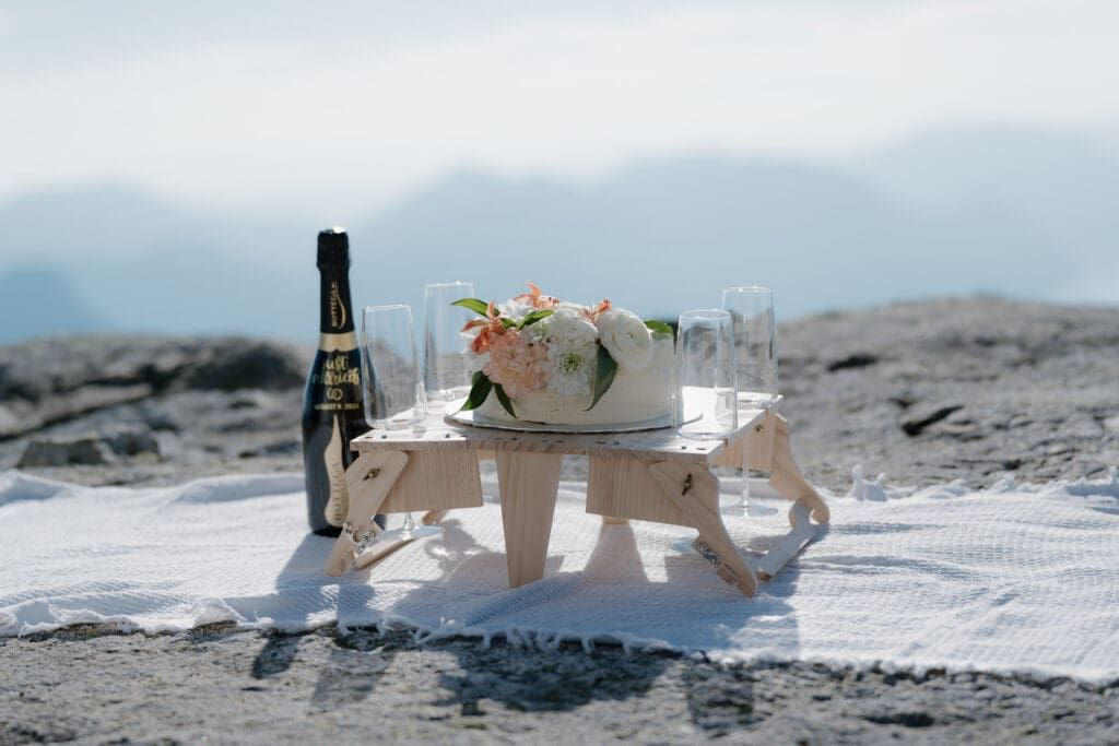 A small table set up with champagne on top of a mountain for the post elopement celebration on Vancouver Island.