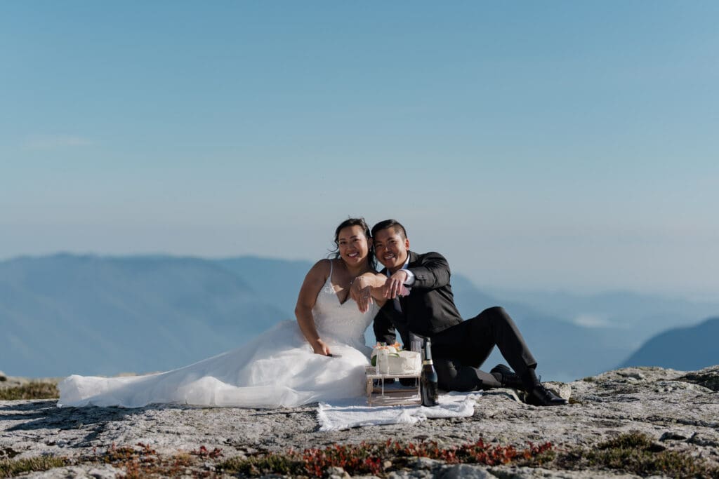 Bride and groom showing off their rings to the camera as they celebrate their luxuriuous helicopter elopement on a mountaintop with cinematic views on Vancouver Island elopement experience
