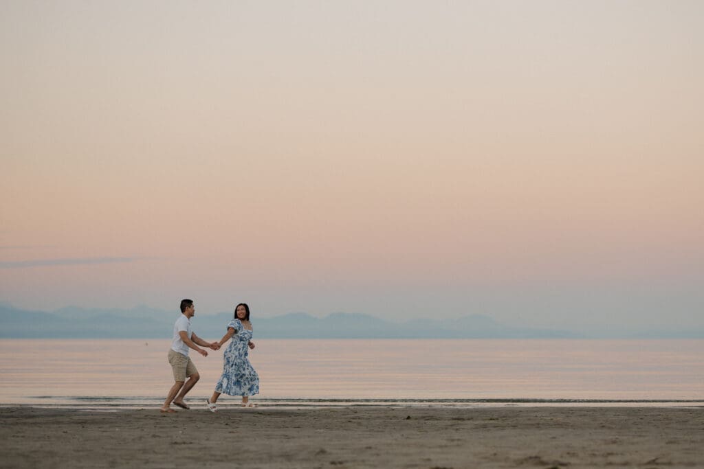Playful engagement photos of couple running along Saratoga Beach at sunset on Vancouver Island