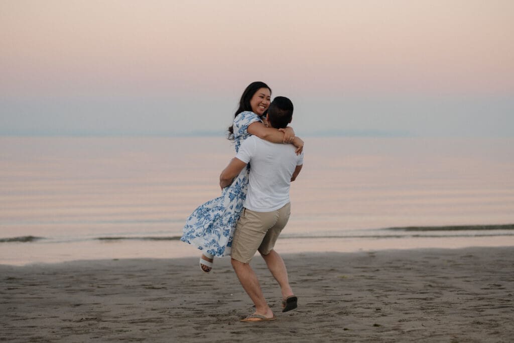 An engaged couple laugh and enjoy each other during their Saratoga Beach engagement photos on Vancouver Island with the beautiful August golden hour sunset in the background.
