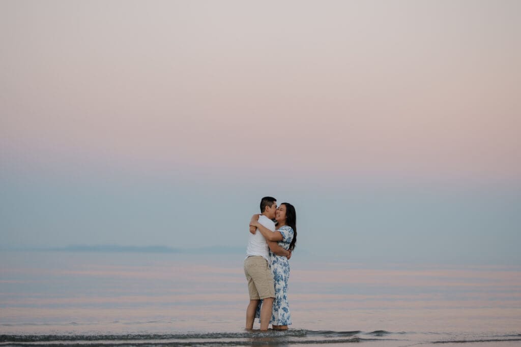 Couple embracing in the ocean during golden hour at Saratoga Beach engagement session on Vancouver Island. Captured by Hayley Zumkeller photography and videography team from Victoria BC.