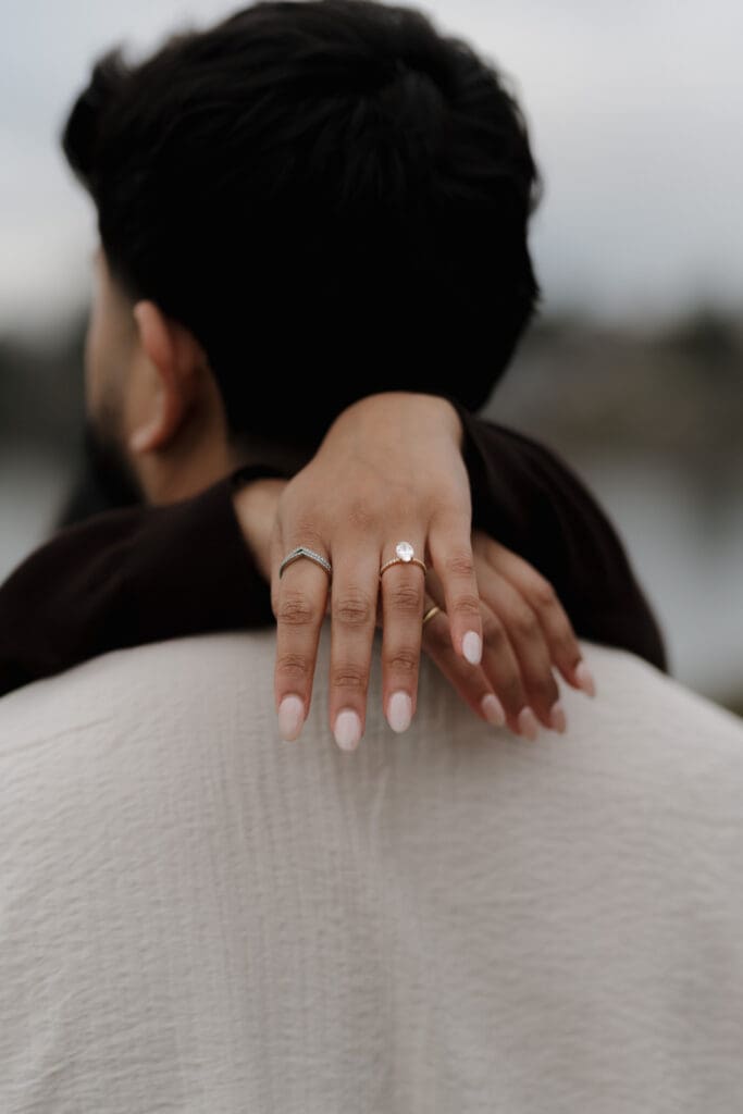 We see a the engagement ring on the newly engaged woman's hand after her surprise proposal at Saxe Point on Vancouver Island.