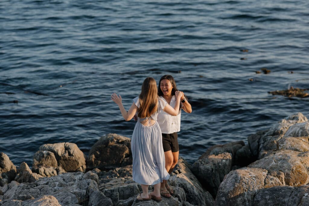 A surprise proposal is celebrated on the rocky ocean side inlet.