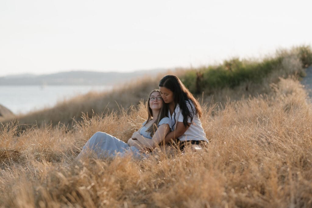 Romantic engagement portraits overlooking the ocean at Saxe Point Park in Victoria BC with warm sunset light and Vancouver Island coastal views
