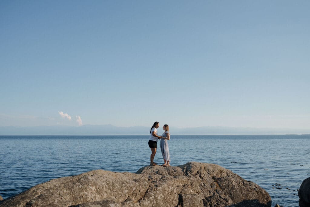 Wide scenic view of Saxe Point Park shoreline at golden hour during a surprise proposal session in Victoria BC with ocean views and rocky coastline on Vancouver Island