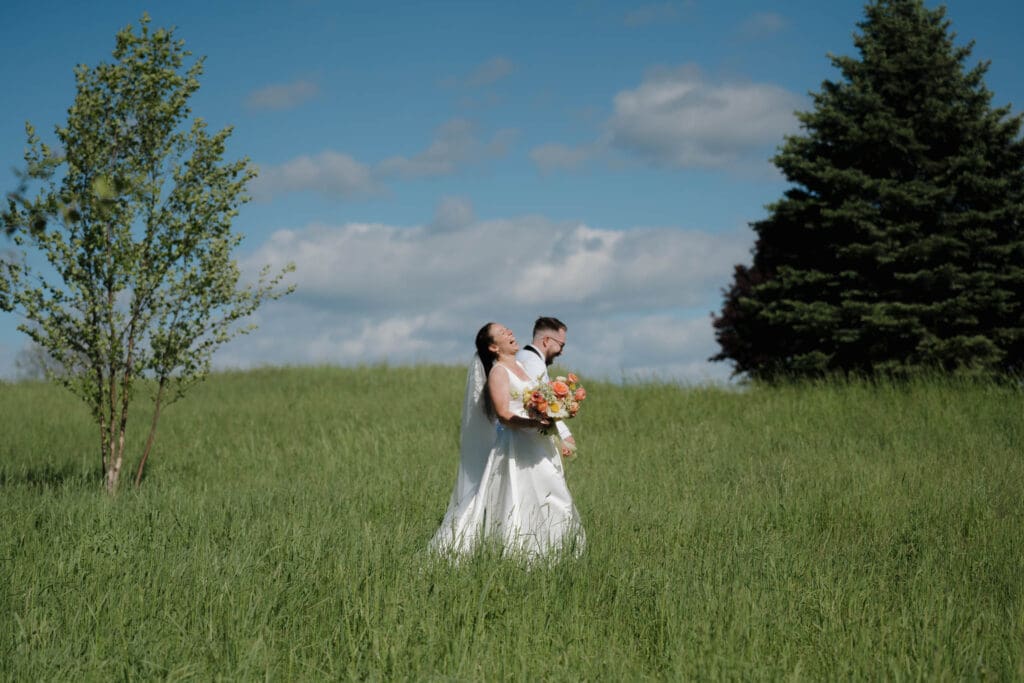 A bride and groom laugh together after their wedding in the fields surrounding Wildflower on Watts in Honesdale PA. Captured by travel wedding photographer Hayley Zumkeller.