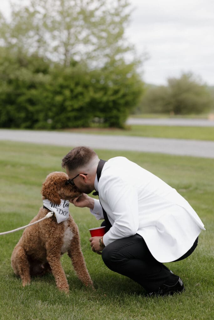 A groom and their dog await the bride for the first look at Wildflower on Watts in Honesdale PA. Captured by travel wedding photographer Hayley Zumkeller.