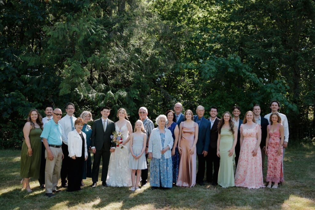 A large family gathered for post ceremony wedding photos on a private family property in Nanaimo BC. Captured by Hayley Zumkeller's Vancouver Island Wedding Videography team.