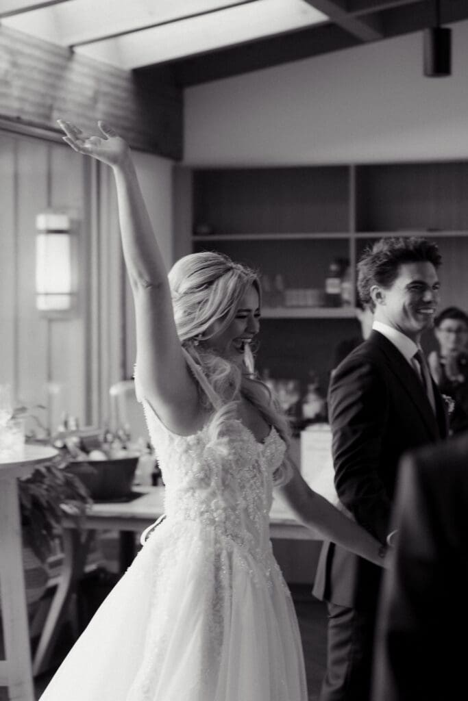 A newly married bride and groom enter their reception full of joy and enthusiasm.