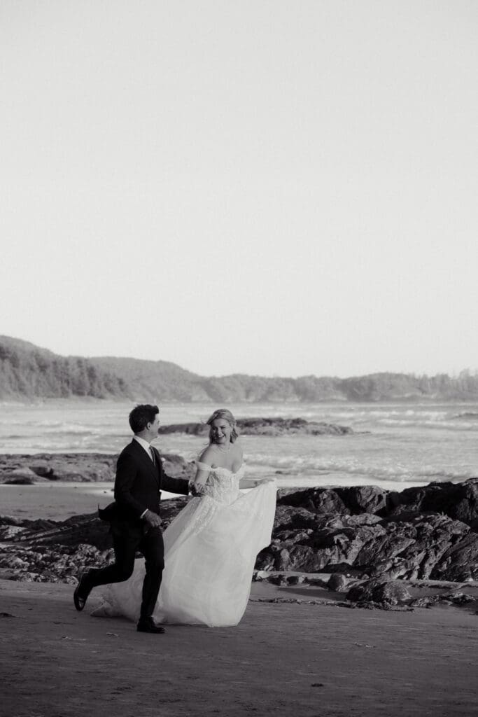 Black and White image of Newlyweds walking along the Pacific Ocean during sunset wedding photos in Tofino BC